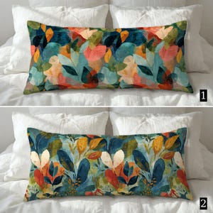 May include: Two rectangular throw pillows with a colorful botanical pattern. The pillows feature a vibrant mix of teal, orange, yellow, and pink leaf designs against a dark blue background. The pillows are placed on white bedding.