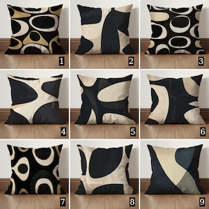 Op de afbeelding: Negen vierkante sierkussens met abstracte patronen in zwart, beige en goud. De ontwerpen omvatten geometrische en organische vormen. De kussens zijn gemaakt van stof en geschikt voor interieurdecoratie.