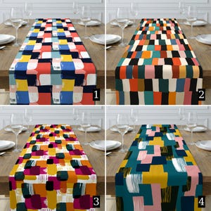 Könnte beinhalten: Vier farbenfrohe Tischläufer mit abstrakten geometrischen Designs. Jeder Läufer hat eine andere Farbpalette: Rot, Blau, Gelb und Weiß; Orange, Türkis, Schwarz und Weiß; Gelb, Pink und Schwarz; und Türkis, Gelb, Pink und Weiß.