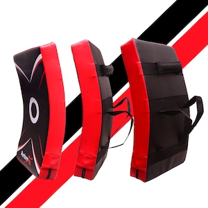May include: Three curved kick pads in red and black with black straps and handles. The pads feature a white circle with a black X design on the front. The text "Perform" is printed on the front of one pad.