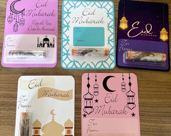 Könnte beinhalten: Fünf bunte Eid Mubarak-Karten mit einem durchsichtigen Plastikfenster zum Einlegen von Geld. Jede Karte zeigt ein anderes Design mit einem Halbmond, einer Moschee und Laternen. Der Text auf den Karten lautet "Eid Mubarak" und "Mögen all deine Gebete erhört werden".