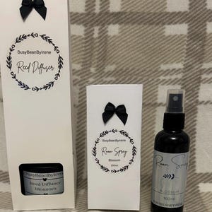May include: A selection of home fragrance products, including a reed diffuser and room spray, presented in white packaging with black bows. The products are labeled with the brand name "BusyBeanByIrene" and the scent "Blossom". The room spray is 100ml.