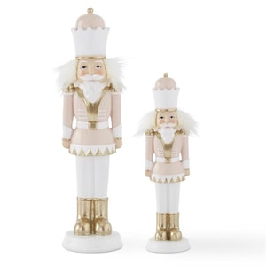 May include: Two pink and white nutcracker figurines with gold accents. The larger nutcracker is standing on a white base and the smaller nutcracker is standing on a white base.