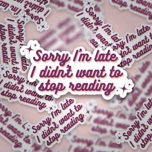 May include: A pink and white sticker with the text "Sorry I'm late I didn't want to stop reading" in a purple font with a white outline. The sticker has a glittery effect.