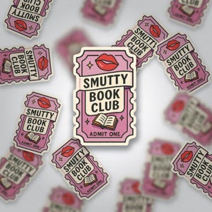 Könnte beinhalten: Rosa- und cremefarbene Aufkleber mit dem Text "SMUTTY BOOK CLUB" und einem Bild roter Lippen und eines offenen Buches. Die Aufkleber haben die Form eines Tickets mit den Worten "ADMIT ONE".