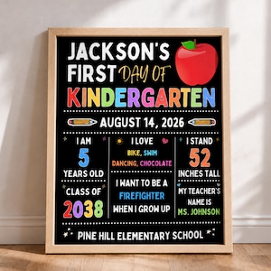 Peut inclure: Une affiche encadrée style tableau noir pour le premier jour de maternelle de Jackson le 14 août 2026. Le poster noir présente une pomme rouge, du texte coloré et des détails incluant l'âge de 5 ans, 52 pouces, des centres d'intérêt et l'école.