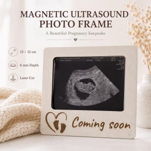 May include: A light-coloured wooden magnetic ultrasound photo frame measuring 13 by 12 cm with a 6 mm depth. The frame features a laser-cut design of a heart with baby footprints and the text "Coming soon" at the bottom, holding an ultrasound image.