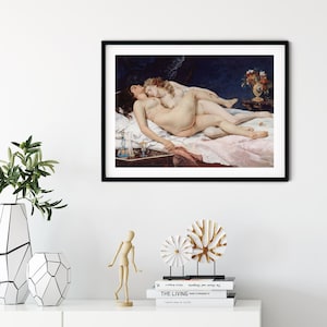 May include: A framed art print featuring a painting of two figures lying together on a bed with white linens. The scene includes a dark blue background, a small table with a vase of flowers, and a bedside table with a blue glass bottle and a goblet.