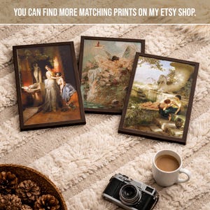 May include: Three rectangular framed art prints featuring classical paintings of figures in outdoor settings, displayed alongside a black vintage-style camera and a white ceramic mug filled with coffee, all arranged on a textured cream surface.