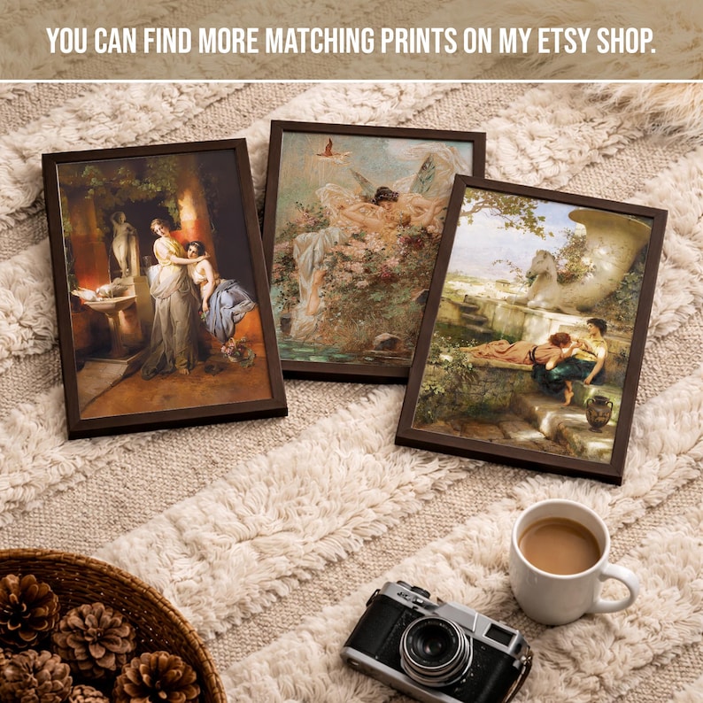 May include: Three rectangular framed art prints featuring classical paintings of figures in outdoor settings, displayed alongside a black vintage-style camera and a white ceramic mug filled with coffee, all arranged on a textured cream surface.