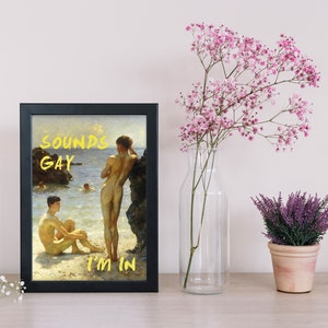 Pode incluir: Uma impress&atilde;o emoldurada de uma pintura que retrata dois homens nus em p&eacute; numa praia. A pintura &eacute; intitulada "Sounds Gay I'm In".