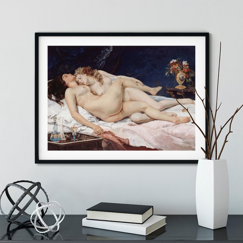 May include: A framed art print depicting a classical oil painting of two figures lying together on a bed with white linens. The scene includes a dark blue background, a small table with a blue glass decanter, and a vase of flowers on a side table.