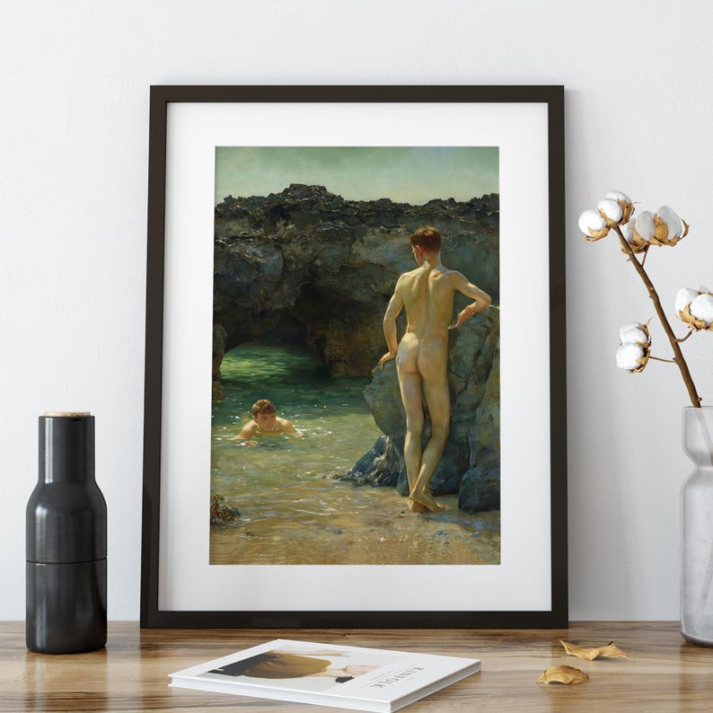 Op de afbeelding: Ingelijste kunstdruk met twee figuren op een rotsachtig strand. E&eacute;n figuur staat op een rots, terwijl een ander in het water zwemt. Het kunstwerk gebruikt een gedempt kleurenpalet met een focus op natuurlijk licht en schaduwen.