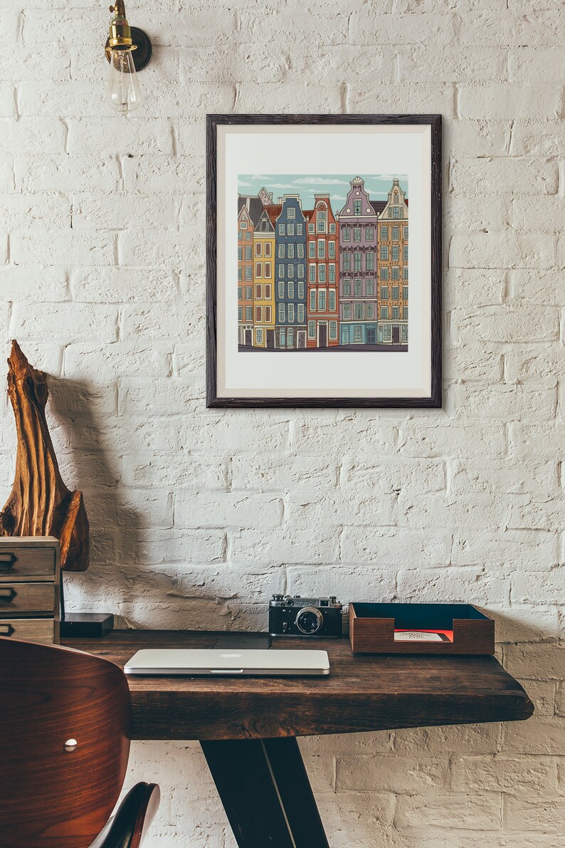 Pu&ograve; includere: Un'illustrazione incorniciata di una fila di edifici colorati con un cielo blu e nuvole bianche sullo sfondo. Gli edifici hanno finestre e porte bianche. L'illustrazione &egrave; su un muro di mattoni bianchi.