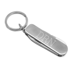 Könnte beinhalten: Silberner Multitool-Schlüsselanhänger mit einem Schlüsselring und den eingravierten Initialen "DRN" an der Seite.