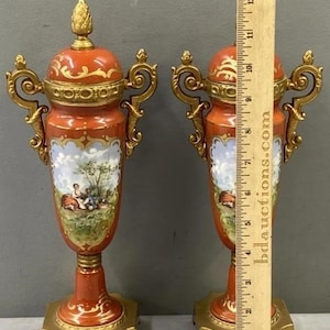 K&ouml;nnte beinhalten: Ein Paar verzierte Porzellanvasen mit goldenen Akzenten und bemalten Szenen. Die Vasen sind etwa 30 cm hoch und haben ein rot-wei&szlig;es Farbschema.
