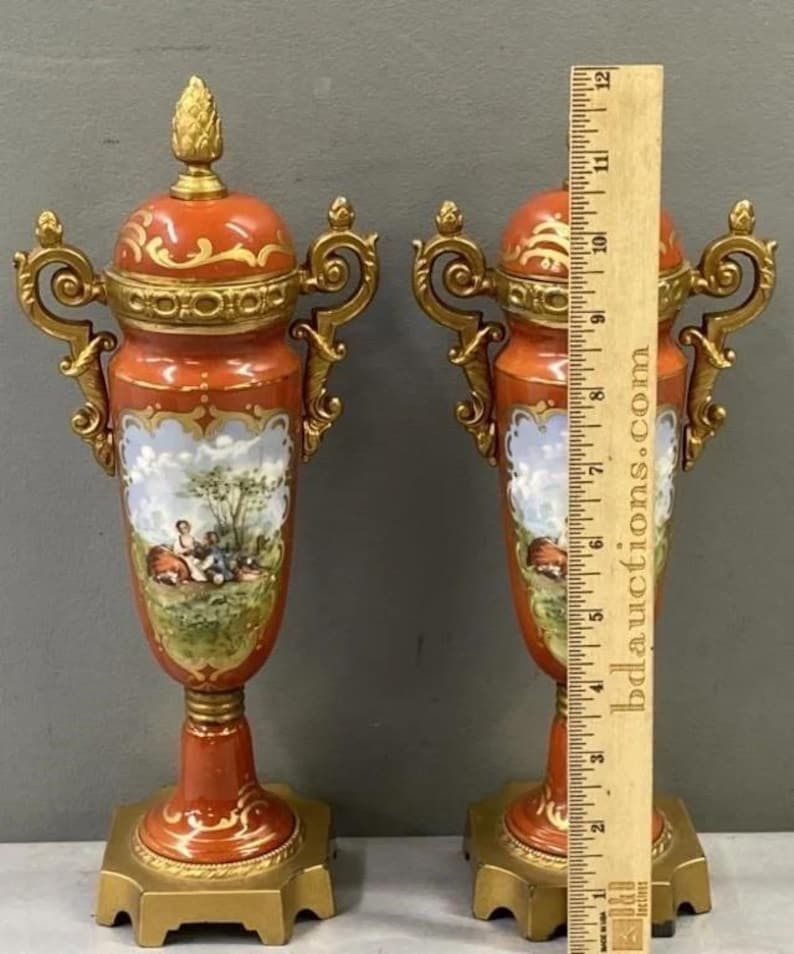 K&ouml;nnte beinhalten: Ein Paar verzierte Porzellanvasen mit goldenen Akzenten und bemalten Szenen. Die Vasen sind etwa 30 cm hoch und haben ein rot-wei&szlig;es Farbschema.