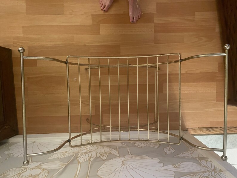 May include: Gold metal towel rack with a curved design and rounded ends. The rack has multiple bars for hanging towels.