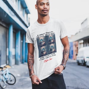 May include: A white t-shirt with a graphic print of an all-seeing eye and the text "Illuminati wants my mind soul and my body. Secret society trying to keep their eye on me. Extra Sauce."