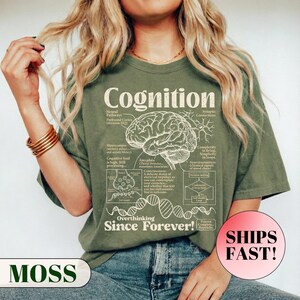 A model wearing a relaxed fit graphic t-shirt featuring a vintage anatomical diagram of a brain, synapses, and a DNA strand. The text reads Cognition and Overthinking Since Forever! with humorous scientific labels like Self-doubt Loop. A funny graphic tee for overthinkers and psychology lovers.