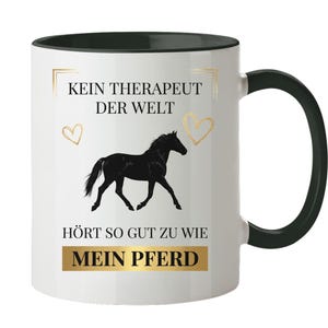 Op de afbeelding: Een witte keramische mok met een zwarte handgreep en zwarte binnenrand. De voorzijde toont een zwart silhouet van een paard, twee gouden hartjes en de Duitse tekst: KEIN THERAPEUT DER WELT HÖRT SO GUT ZU WIE MEIN PFERD, met de laatste twee woorden gemarkeerd.