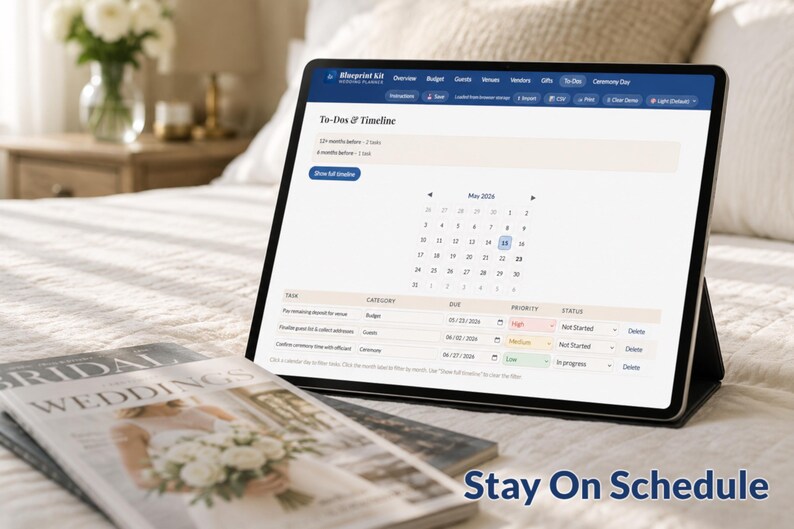 May include: A digital tablet displaying a wedding planning timeline and calendar, with the text "Stay On Schedule." A bridal magazine is in the foreground. The tablet is propped up on a bed with a floral arrangement in the background.
