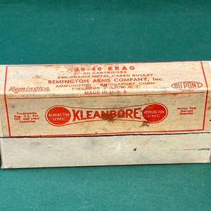 May include: Vintage Remington Kleanbore ammunition box. The box is off-white with red lettering and graphics, including the Remington UMC logo and the text "30-40 KRAG". The box is labeled "20 Cartridges" and "Made in U.S.A."