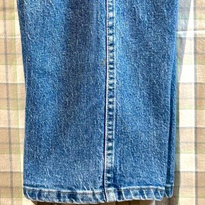 K&ouml;nnte beinhalten: Nahaufnahme des unteren Saums einer blauen Jeans. Die Jeans hat einen geraden Schnitt und eine klassische Passform.