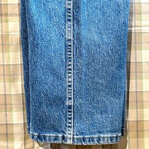 K&ouml;nnte beinhalten: Eine blaue Jeanshose, die in der H&auml;lfte gefaltet ist und die Naht an der R&uuml;ckseite der Beine zeigt.