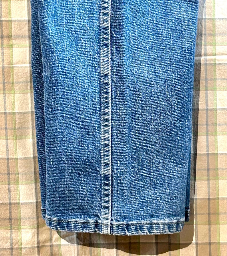 K&ouml;nnte beinhalten: Eine blaue Jeanshose, die in der H&auml;lfte gefaltet ist und die Naht an der R&uuml;ckseite der Beine zeigt.