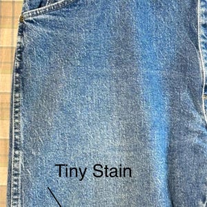 K&ouml;nnte beinhalten: Eine blaue Jeanshose mit einem kleinen, hellen Fleck auf der Vorderseite. Die Jeans hat einen klassischen F&uuml;nftaschen-Stil und eine gerade Beinpartie.