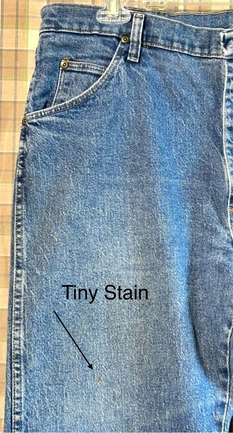 K&ouml;nnte beinhalten: Eine blaue Jeanshose mit einem kleinen, hellen Fleck auf der Vorderseite. Die Jeans hat einen klassischen F&uuml;nftaschen-Stil und eine gerade Beinpartie.