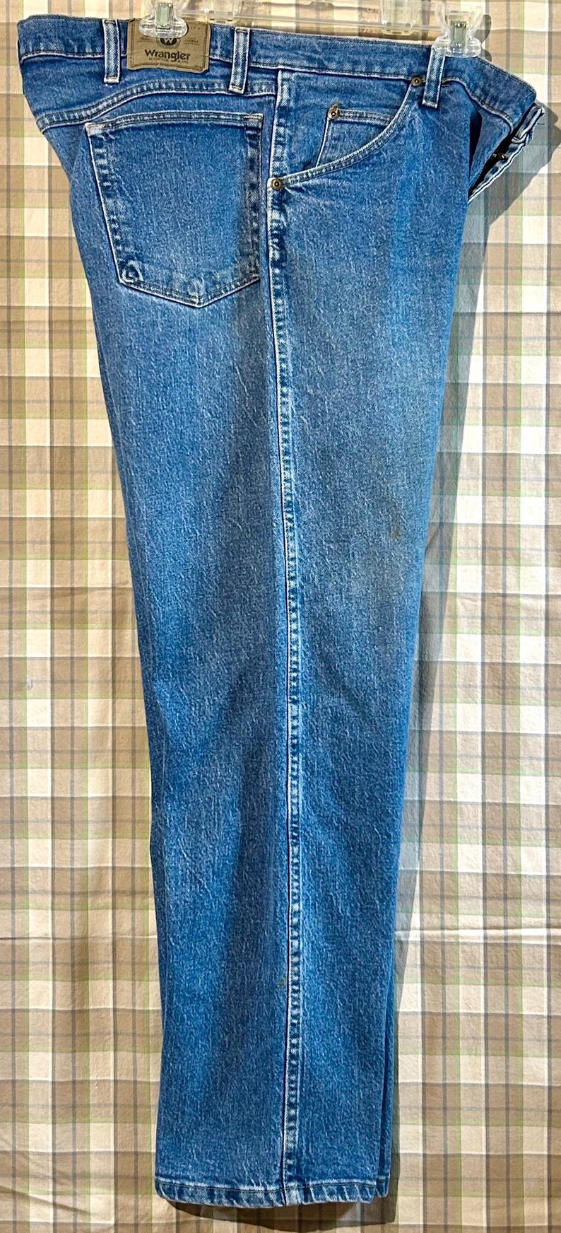 K&ouml;nnte beinhalten: Eine blaue Jeanshose mit einem braunen Leder-Wrangler-Etikett auf der Ges&auml;&szlig;tasche.