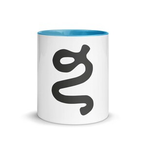 Può includere: Una tazza in ceramica bianca con interno e bordo di colore blu brillante. La superficie esterna presenta un grande e audace grafico nero a forma di lettera g minuscola stilizzata e sinuosa, centrata sulla parte anteriore del contenitore.