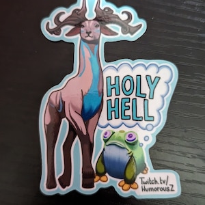 May include: A sticker featuring a cartoon deer with large antlers and a blue and pink body. The deer is standing next to a green frog with a thought bubble that says "HOLY HELL". The sticker has a blue background and the text "Twitch.tv/HumorousZ" in the bottom right corner.
