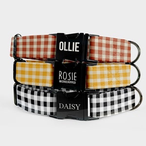May include: Three dog collars with black buckles and gingham patterns. The top collar is red and white, the middle collar is yellow and white, and the bottom collar is black and white. The buckles have the names "Ollie", "Rosie Microchipped", and "Daisy" printed on them.