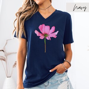 May include: A navy blue t-shirt with a pink watercolor flower graphic. The shirt has a v-neck and short sleeves.