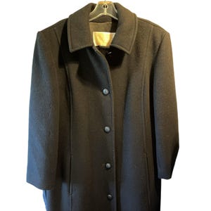 May include: A long black wool coat with a collar and button closure.