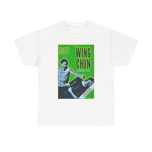 Op de afbeelding: Wit t-shirt met een groen en zwart ontwerp met de tekst "WING CHUN KUNG-FU". De afbeelding toont twee mensen in een vechtsportpose. De tekst op de afbeelding luidt "Technical Editor Bruce Lee By A. Yimm Lee".