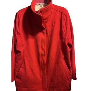 May include: A bright red coat with a high collar and two front pockets. The coat has a button closure and a light-colored lining. The coat is made of a thick, textured material.