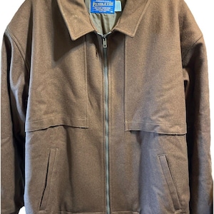Könnte beinhalten: Braune Wolljacke mit durchgehendem Reißverschluss und Kragen. Die Jacke hat zwei Vordertaschen sowie gerippte Bündchen und Saum. Das Etikett lautet "PENDLETON".