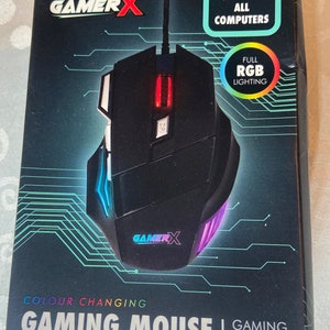 May include: A black GamerX gaming mouse with colour-changing RGB lighting. The box states "Compatible with All Computers" and "Gaming Mouse". The mouse has a sleek design with multiple buttons and a scroll wheel, suitable for gaming.