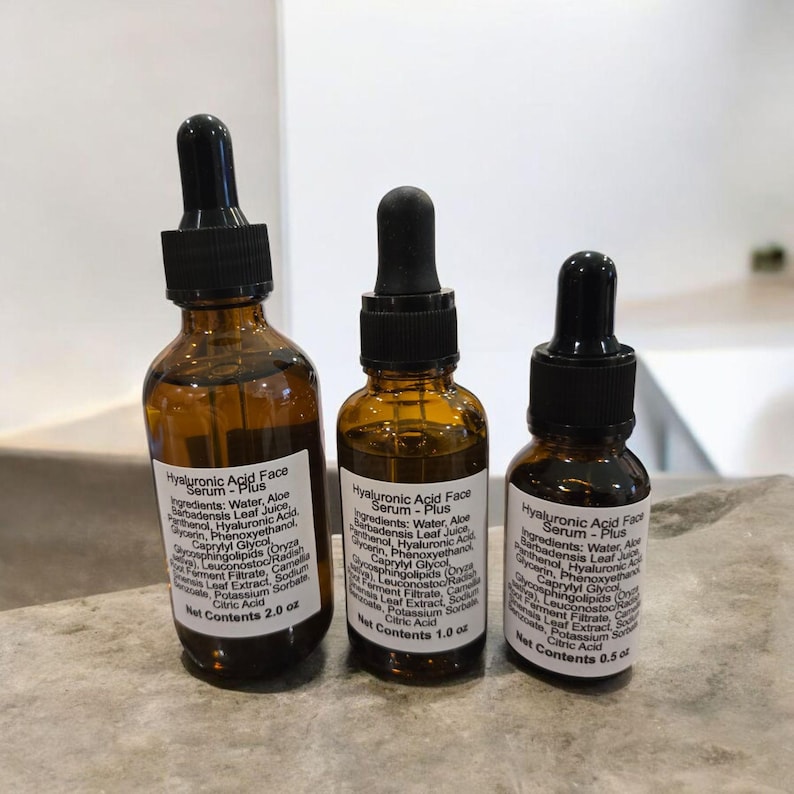 Peut inclure: Trois flacons en verre ambr&eacute; avec des compte-gouttes contenant du s&eacute;rum pour le visage &agrave; l'acide hyaluronique - Plus. Les flacons sont &eacute;tiquet&eacute;s avec le nom du produit, les ingr&eacute;dients et le contenu net. Les flacons sont dispos&eacute;s en rang&eacute;e du plus grand au plus petit, le plus grand flacon contenant 2,0 oz, le flacon du milieu contenant 1,0 oz et le plus petit flacon contenant 0,5 oz.