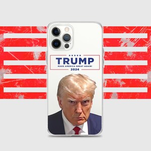May include: A clear phone case with a white background and a picture of Donald Trump. The text "TRUMP" is in blue with five stars above it. Below the text is "MAKE AMERICA GREAT AGAIN!" in blue and "2024" in blue below that. The background is a red, white, and blue American flag.