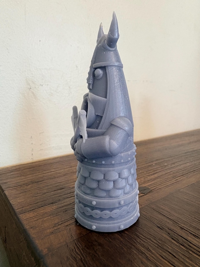 Op de afbeelding: Een grijs 3D-geprint beeldje van een krijger met een gehoornde helm die een bijl vasthoudt. Het figuur heeft een getextureerde tuniek met schubbenpatroon, een riem met ronde noppen en een decoratieve band rond de basis, alles in mat grijs.