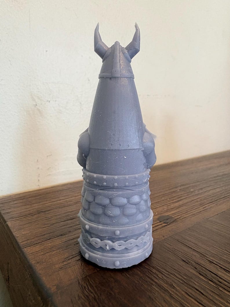 Op de afbeelding: Een lichtpaars, 3D-geprint beeldje van een krijger met een gehoornde helm. Het figuur heeft een gestructureerd, schubachtig patroon rond het middengedeelte, een riem met kleine noppen en een decoratieve band bij de basis. Het ontwerp is conisch.