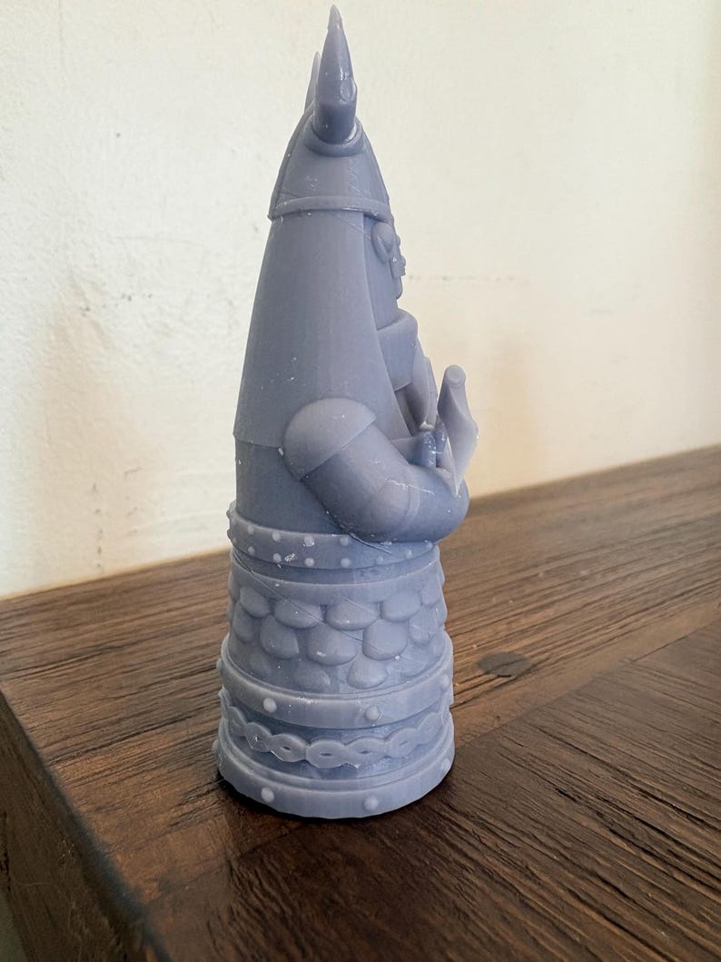 Op de afbeelding: Een lichtgrijs 3D-geprint beeldje van een krijger met een gehoornde helm en harnas. Het figuur heeft een conische helm, een borststuk met schubbenpatroon en een riem met een gevlochten ontwerp. De krijger is in profiel afgebeeld en houdt een voorwerp.