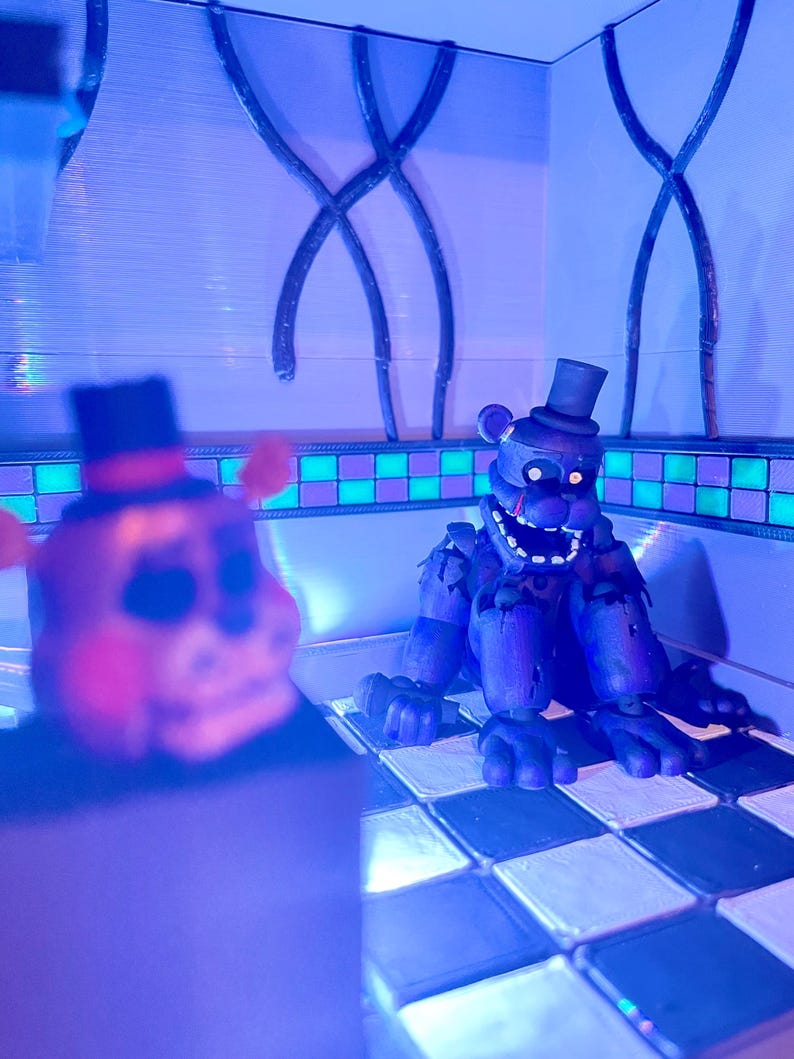 Op de afbeelding: Twee beerachtige figuren met hoge hoeden staan in een kamer met een geblokte vloer. E&eacute;n figuur staat onscherp op de voorgrond, terwijl de andere op de achtergrond staat, met een verweerd, donkerblauw uiterlijk en een open mond.