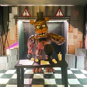 May include: A brown animatronic bear figure with a black top hat and bowtie stands behind a black desk. The figure has glowing yellow eyes, a wide mouth with visible teeth, and distressed brown plating. The desk holds papers and a cup.
