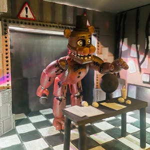 May include: A brown bear animatronic figure wearing a black top hat and bowtie, holding a microphone. The figure stands in a room with a black and white chequered floor, a black desk with papers, a small cup, and a circular object, with a warning sign.